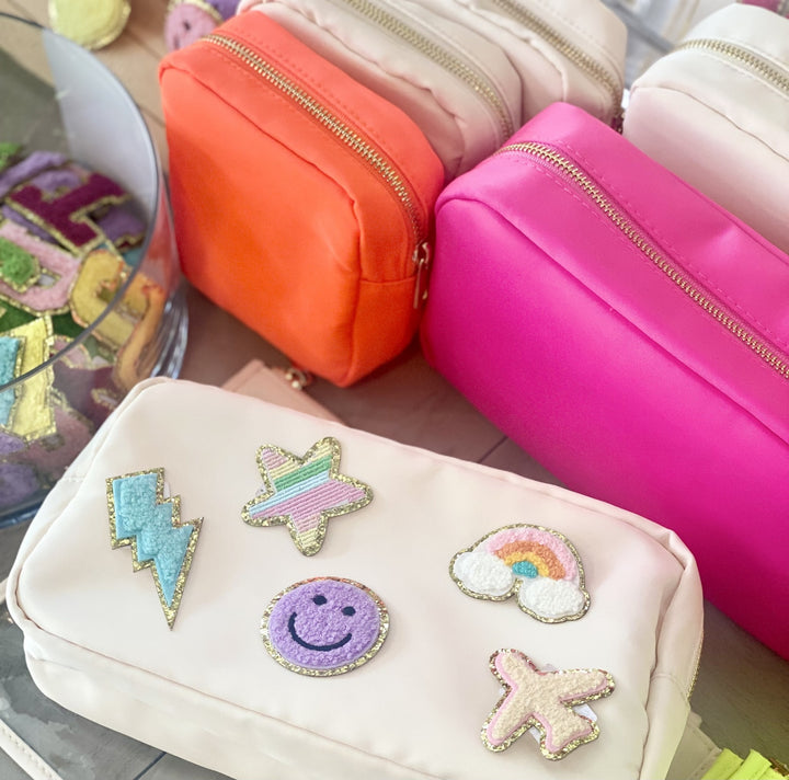 An orange nylon pouch with a gold zipper, surrounded by other colorful pouches.