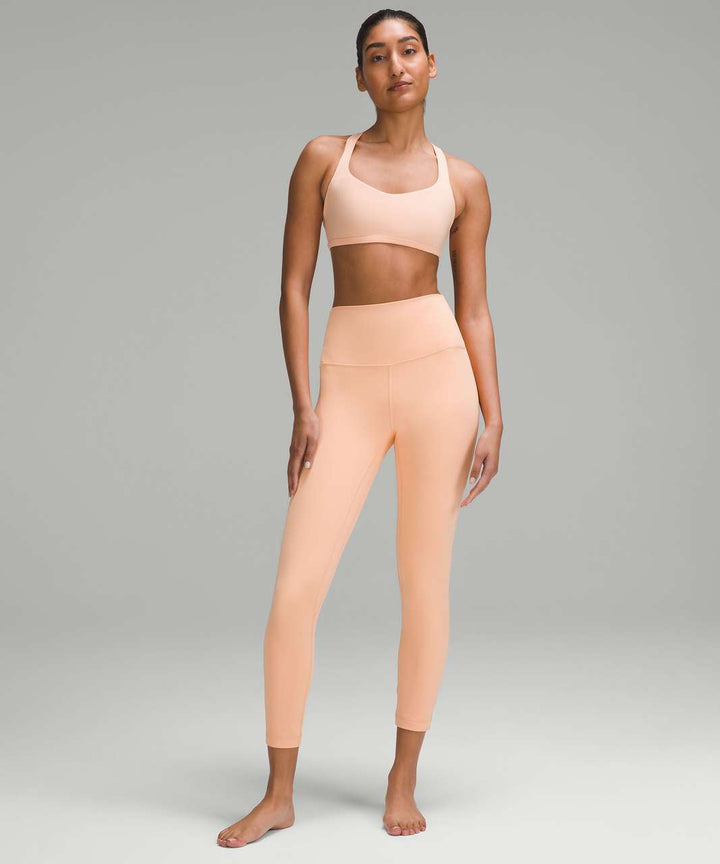 A woman models lululemon Align High-Rise 25" leggings and sports bra in Peach Bellini.