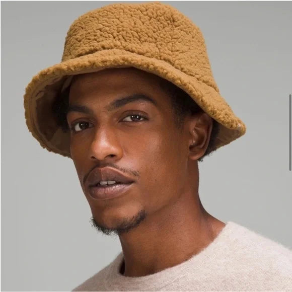 A man wears a textured fleece bucket hat in allspice.
