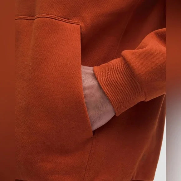Orange hoodie with a hand in the kangaroo pocket.