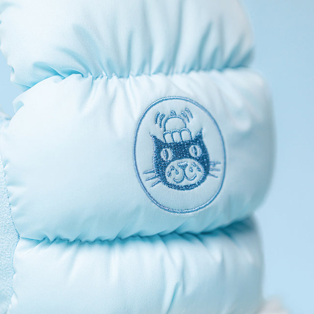 A light blue puffer jacket features a circular embroidered patch of a cat wearing a crown.
