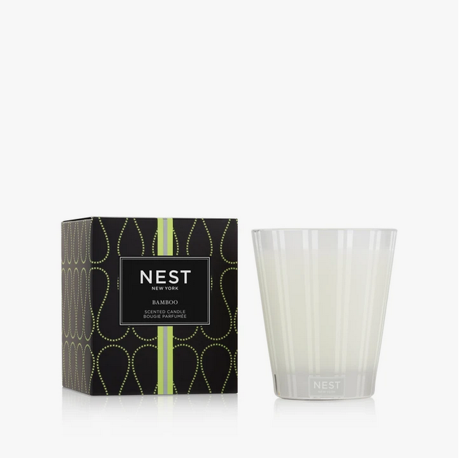 A Nest New York Bamboo Classic Candle in its box next to the striped glass vessel.