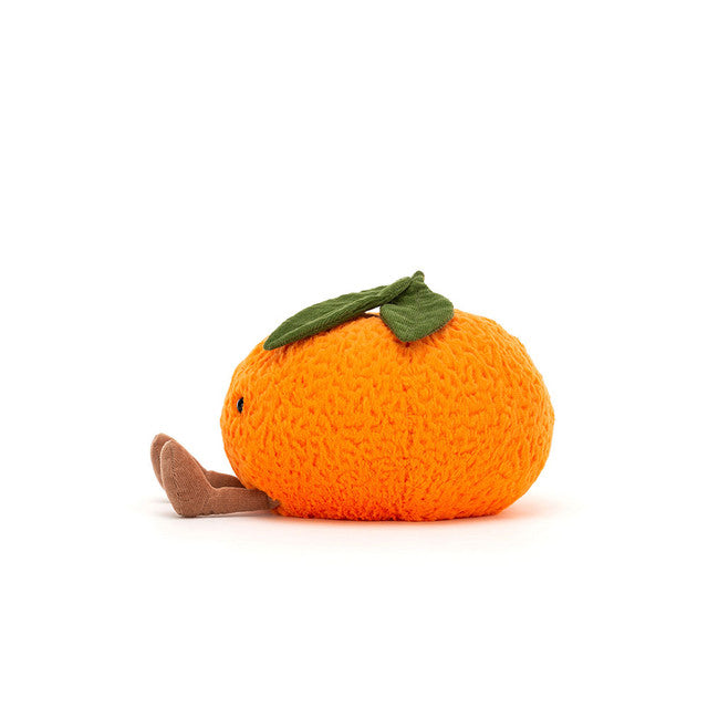 A plush orange clementine with green leaves and small brown legs sits on a white background.