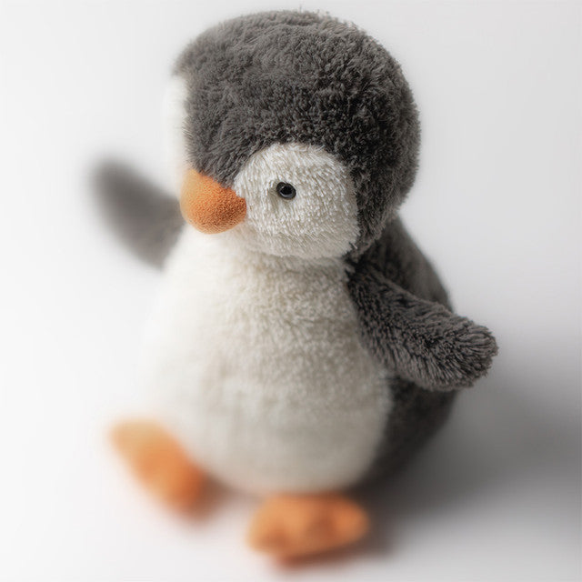 A small, plush gray and white penguin with an orange beak and feet sits facing forward.