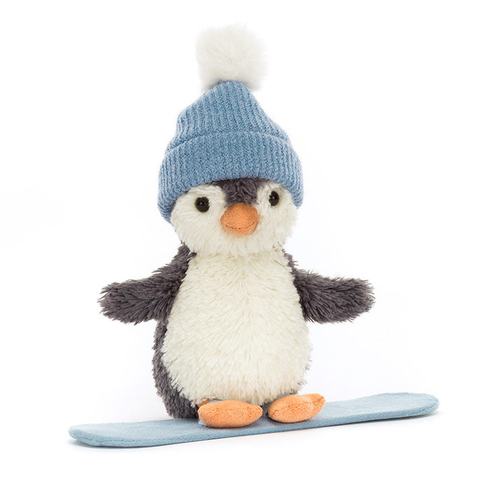 A plush penguin wearing a blue bobble hat stands on a blue snowboard.