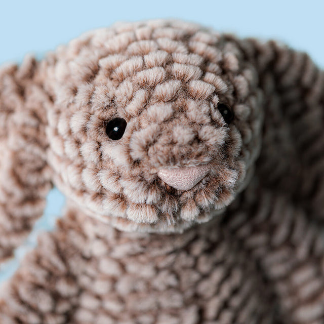 A close-up of a soft, brown plush bunny with black eyes and a pink nose.