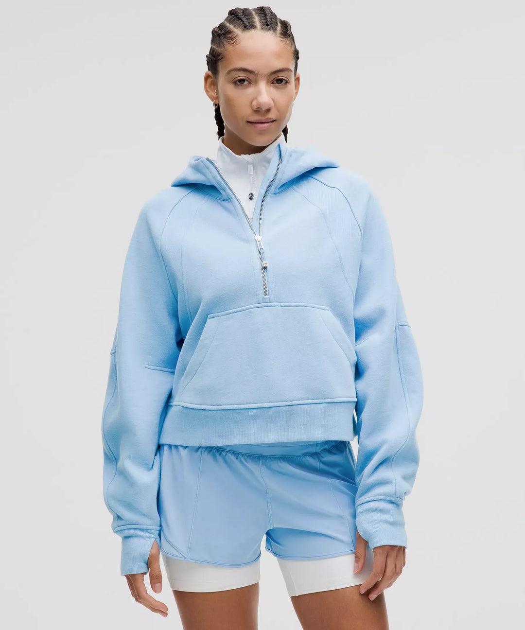 A woman wears a light blue oversized half-zip hoodie and matching shorts.