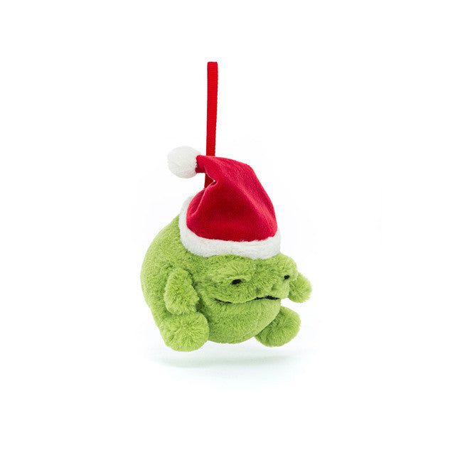 A green plush frog ornament wearing a red Santa hat hangs from a red ribbon.