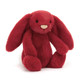 A plush red bunny with long ears and a light pink nose sits facing forward.