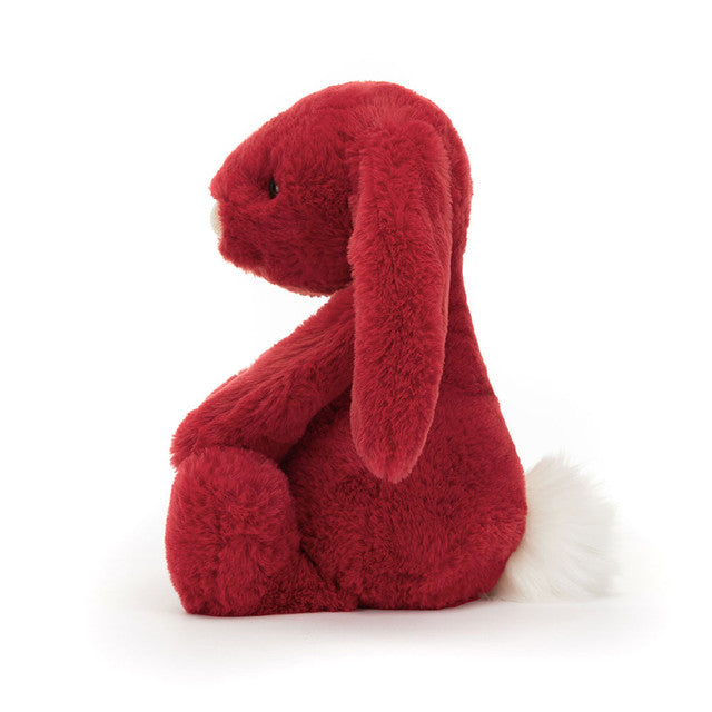 A red plush bunny with long ears and a white fluffy tail sits facing left.