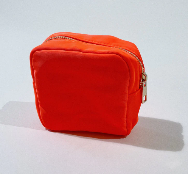 The Small Pouch Orange, a bright orange nylon pouch with a gold zipper.