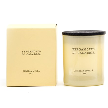 An ivory candle in a glass jar with a dark lid, next to its matching box.