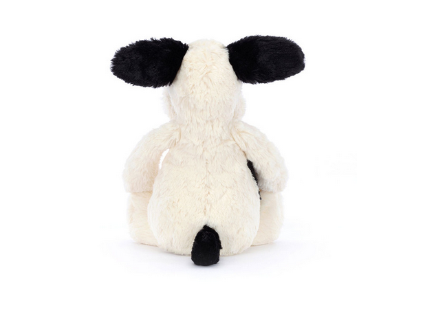 A cream and black puppy plush toy is shown from the back, sitting.