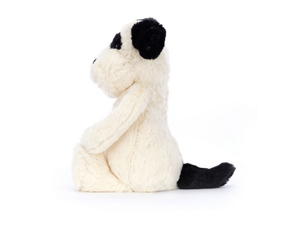 A cream and black puppy plush toy sits facing left.