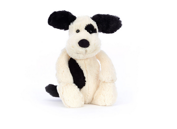 A cream and black plush puppy with floppy black ears and a black spot over one eye.