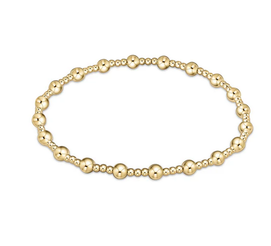 A gold beaded bracelet with alternating large and small beads.