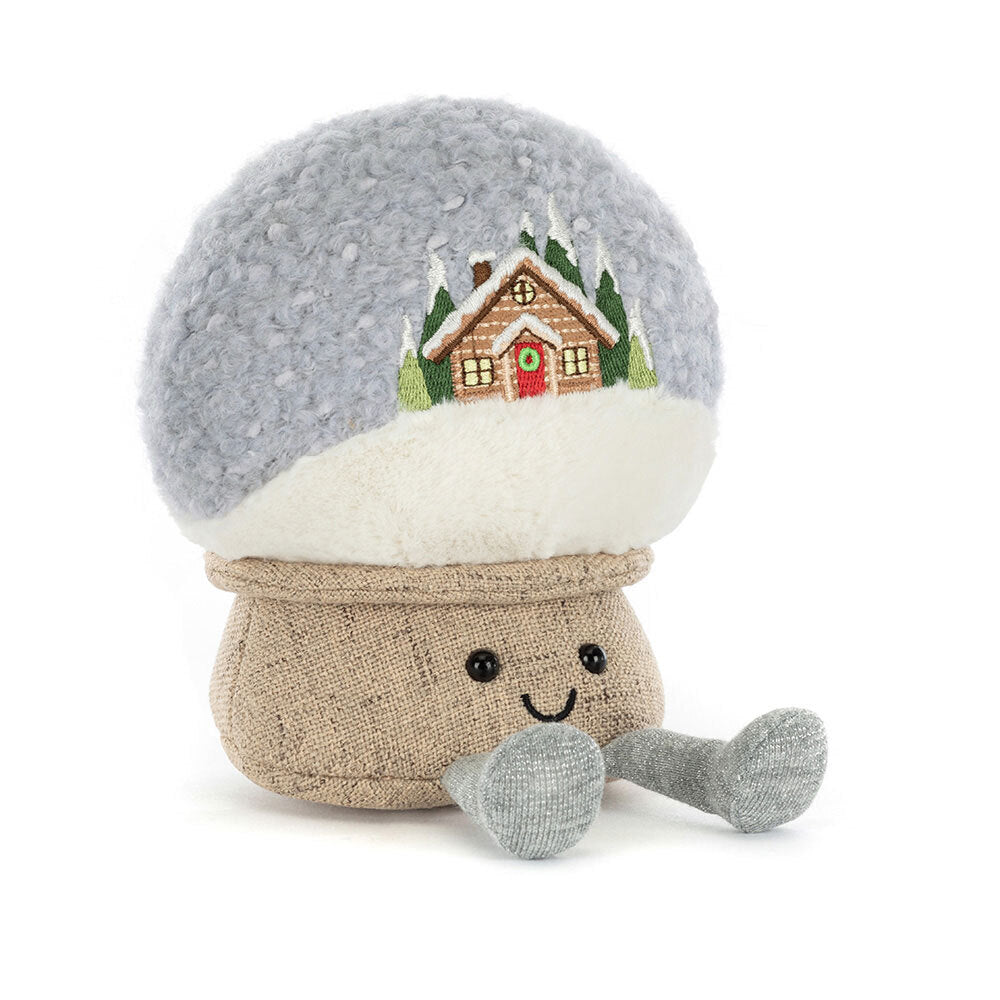 A plush snow globe with an embroidered cabin scene and a smiling face.