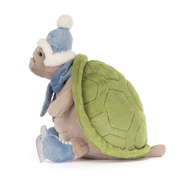 A plush turtle wearing a blue winter hat, scarf, and ice skates.