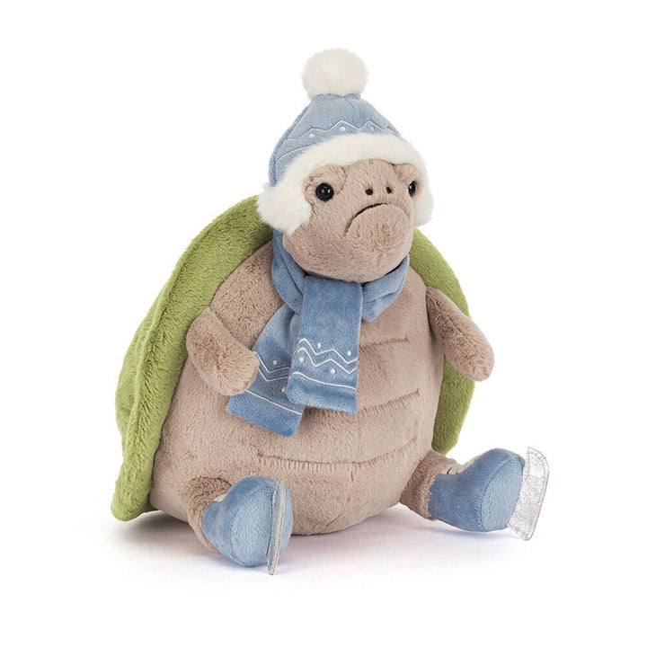 A plush turtle wearing a blue winter hat, scarf, and ice skates.