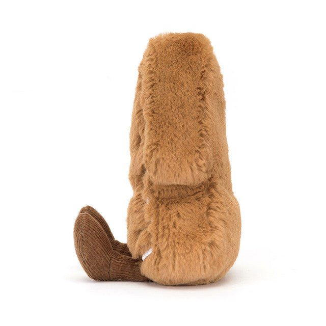 A brown plush tree cookie with corduroy feet sits facing away.